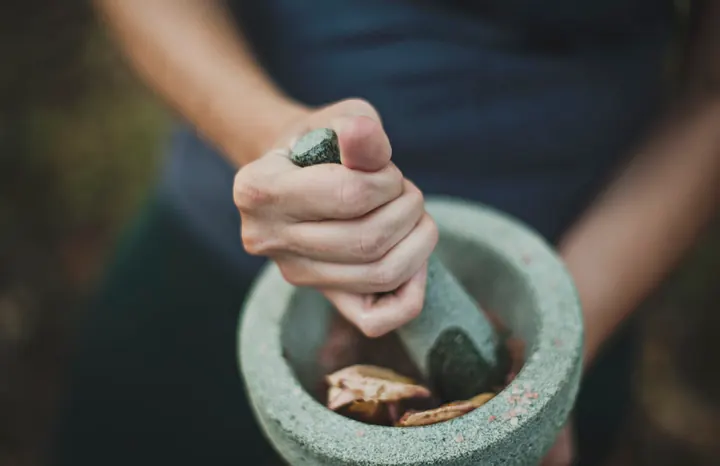 Traditional stone mortar and pestle grinding whole spices